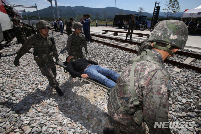 [강릉=뉴시스]김경목 기자 = 2019년도 국가위기 대응연습 실제훈련 모습. 육군 장병들이 부상당한 승객들을 들것을 이용해 구급차로 옮기고 있다. 훈련은 강릉선 고속열차가 지진으로 탈선해 화재가 발생한 상황을 가정해 실시됐다. 2019.05.28.photo31＠newsis.com