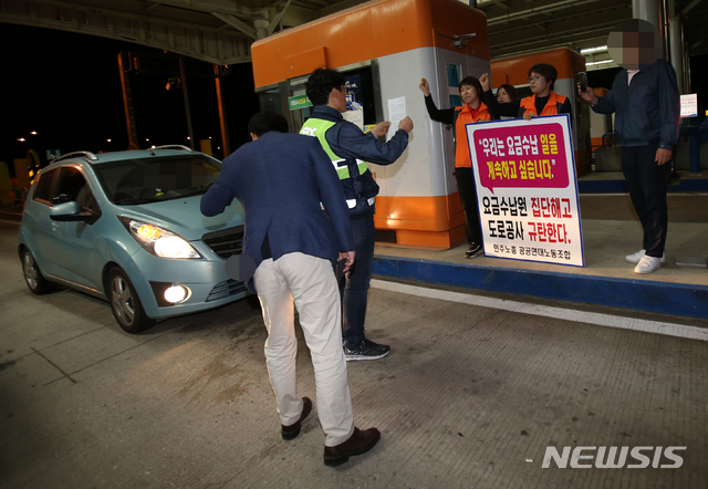 【강릉=뉴시스】김경목 기자 = 한국도로공사 강릉지사 옥계요금소 관계자가 1일 오전 강원 강릉시 옥계면 옥계요금소에서 자회사 설치에 반대하는 노동자들에게 계약 해지에 따른 해고 사실을 통보하고 있다. 또 다른 도로공사 관계자들은 스마트폰으로 촬영하고 있고 수납차로에 들어온 차량을 세웠다. 2019.06.01.&nbsp;&nbsp; photo31＠newsis.com