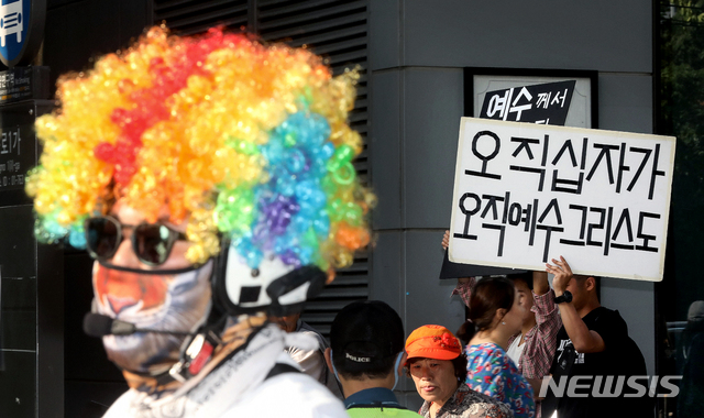 【서울=뉴시스】김병문 기자 = 1일 오후 서울 중구 명동·을지로 일대에서 열린 서울퀴어문화축제 퍼레이드 참가자 뒤로 동성애 반대 피켓을 든 시민이 지나가고 있다. 2019.06.01.&nbsp;&nbsp; dadazon@newsis.com