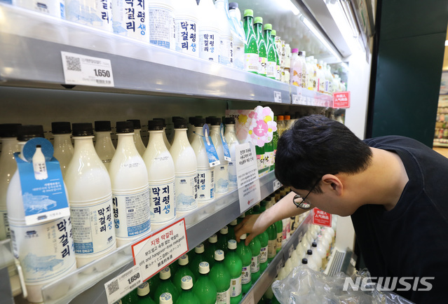 【서울=뉴시스】 전진환 기자 = 정부는 2017년과 2018년 출고량과 세액을 바탕으로 맥주의 기준세율을 ℓ당 830.3원으로 정했으며 막걸리를 포함한 탁주의 경우 ℓ당 41.7원으로 결정했다.&nbsp; 양을 기준으로 세금이 부과되면서 캔ㆍ병ㆍ페트ㆍ케그(생맥주) 등 용기별로 세부담이 달라진다. 국내에서 맥주를 생산하는 3사(OB맥주ㆍ하이트진로ㆍ롯데주류) 기준 캔맥주에 부과되는 주세는 ℓ당 830원으로 현재보다 291원 저렴해진다. 그만큼 가격이 내려갈 여지가 생겨수입맥주처럼 국산 캔맥주도 이른바 '4캔에 만원' 행사를 할 수 있게 됐다. 5일 서울의 한 마트에서 주류 관계자가 막걸리를 진열하고 있다. 2019.06.05.&nbsp; amin2@newsis.com 