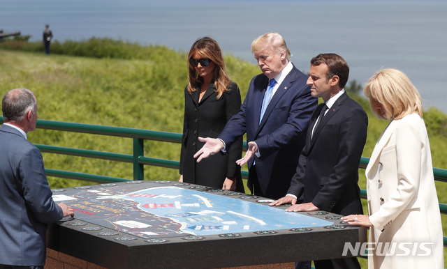 트럼프 대통령 부처와 마크롱 대통령 부처가 노르망디 미군 상륙해변인 오마하가 바라다보이는 구릉위에 조성된 9000명의 미 전몰용사 묘지에서 상륙작전 설명을 듣고 있다&nbsp;&nbsp; AP