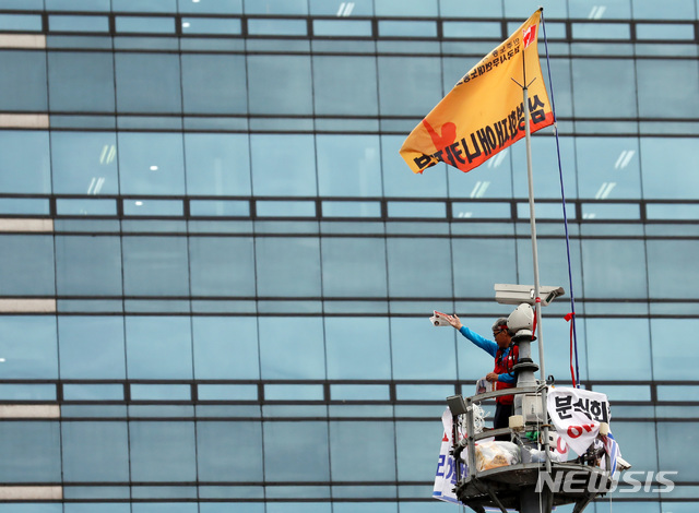 【서울=뉴시스】이영환 기자 = 지난 6월10일 삼성해고자복직투쟁위원회 소속 김용희(61)씨가 서울 강남구 지하철 강남역 사거리 교통 폐쇄회로(CCTV)철탑에 현수막을 내걸고 올라가 고공 농성을 벌이고 있다. 2019.06.10. 20hwan@newsis.com