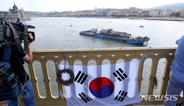 【부다페스트(헝가리)=뉴시스】추상철 기자 =11일 오후(현지시각) 헝가리 부다페스트 다뉴브강 유람선 침몰 사고현장에서 바지선에 실려 이동되는 침몰 유람선 허블레아니호 앞으로 태극기가 보이고 있다. 2019.06.11. scchoo@newsis.com