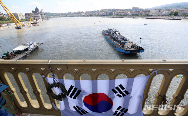 【부다페스트(헝가리)=뉴시스】추상철 기자 =11일 오후(현지시각) 헝가리 부다페스트 다뉴브강 유람선 침몰 사고현장에서 바지선에 실려 이동되는 침몰 유람선 허블레아니호 앞으로 태극기가 보이고 있다. 2019.06.11. scchoo@newsis.com
