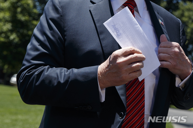 【워싱턴=AP/뉴시스】도널드 트럼프 미국 대통령이 11일(현지시간) 재생에너지 관련 연설을 위해 아이오와주로 이동하기에 앞서 기자들의 앞에서 김정은 위원장의 친서로 보이는 서류 한장을 꺼내고 있다. 그는 김정은 북한 국무위원장으로부터 아름답고 따뜻한 친서를 받았다고 밝혔다. 2019.06.12