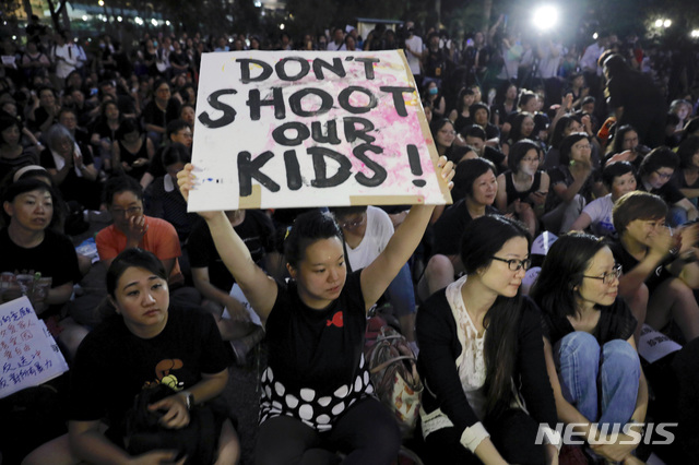 【홍콩=AP/뉴시스】14일 홍콩 차터가든 공원에서 '범죄인 인도 법안' 개정 반대 시위가 열린 가운데 한 시위자가 '우리 아이들에게 총을 쏘지 말라'는 피켓을 높이 들고 있다. 주최측 추산 6000명이 참석한 이날 행사에서는 5·18 광주민주화운동을 상징하는 가요인 '임을 위한 행진곡'이 울렸다. 2019.06.15