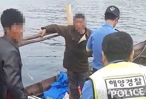 【서울=뉴시스】 삼척 북한 목선 파장이 갈수록 커지고 있는 21일 지난 15일 오전 6시 50분, 삼척항 방파제에 북한 어선이 왔다는 신고에 삼척 파출소 경찰들이 목선을 타고 온 북한 주민들을 조사하고 있다.&nbsp; 해경은 19분이 지난 7시 9분에 첫 보고서를 청와대, 국정원, 합참 등에 북한 어선이 자체 동력으로 삼척항에 입항했다고 보고 했다. 하지만 군은 17일 첫 발표에서 어선 발견 지점을 '삼척항 인근'이라고만 했고, 표류라고 명시해, 자체 동력으로 배가 움직인 것도 숨겨 논란이 되고 있다. 2019.06.21. (사진= 독자 제공)&nbsp; photo@newsis.com 