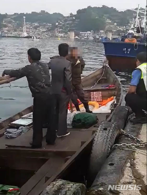 【서울=뉴시스】 삼척 북한 목선 파장이 갈수록 커지고 있는 21일 지난 15일 오전 6시 50분, 삼척항 방파제에 북한 어선이 왔다는 신고에 삼척 파출소 경찰들이 목선을 타고 온 북한 주민들을 조사하고 있다.&nbsp; 해경은 19분이 지난 7시 9분에 첫 보고서를 청와대, 국정원, 합참 등에 북한 어선이 자체 동력으로 삼척항에 입항했다고 보고 했다. 하지만 군은 17일 첫 발표에서 어선 발견 지점을 '삼척항 인근'이라고만 했고, 표류라고 명시해, 자체 동력으로 배가 움직인 것도 숨겨 논란이 되고 있다. 2019.06.21. (사진= 독자 제공) photo@newsis.com