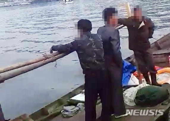 【서울=뉴시스】 삼척 북한 목선 파장이 갈수록 커지고 있는 21일 지난 15일 오전 6시 50분, 삼척항 방파제에 북한 어선이 왔다는 신고에 삼척 파출소 경찰들이 목선을 타고 온 북한 주민들을 조사하고 있다.&nbsp; 해경은 19분이 지난 7시 9분에 첫 보고서를 청와대, 국정원, 합참 등에 북한 어선이 자체 동력으로 삼척항에 입항했다고 보고 했다. 하지만 군은 17일 첫 발표에서 어선 발견 지점을 '삼척항 인근'이라고만 했고, 표류라고 명시해, 자체 동력으로 배가 움직인 것도 숨겨 논란이 되고 있다. 2019.06.21. (사진= 독자 제공)&nbsp; photo@newsis.com
