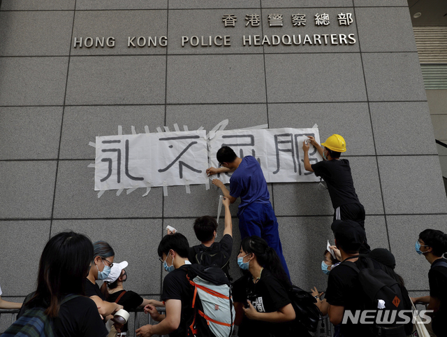  【홍콩=AP/뉴시스】 홍콩 시위대가 21일 홍콩 경찰본부 벽에 "절대 지지 않는다"는 글씨를 붙여놓고 있다. 사우스차이나모닝포스트(SCMP)는 시민 1000여명이 '법죄인 인도 법안'의 완전한 철회를 요구하며 21일 다시 시위에 나섰다고 보도했다. 2019.06.21. 