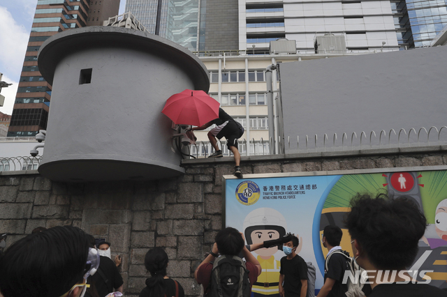 【홍콩=AP/뉴시스】범죄인 인도법 반대 시위자가 21일 오후 보안 카메라를 무력화하기 위해 홍콩 경찰본부 청사 외벽을 기어올라가고 있다. 지난 2014년 홍콩 우산시위를 주도했던 조슈아 웡은 시위대에게 경찰본부를 에워싸줄 것을 요청했다. 2019.06.21