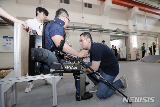 영남대 로봇기계공학과 최정수(오른쪽) 교수가 웨어러블 로봇 워크온슈트를 점검하고 있다.