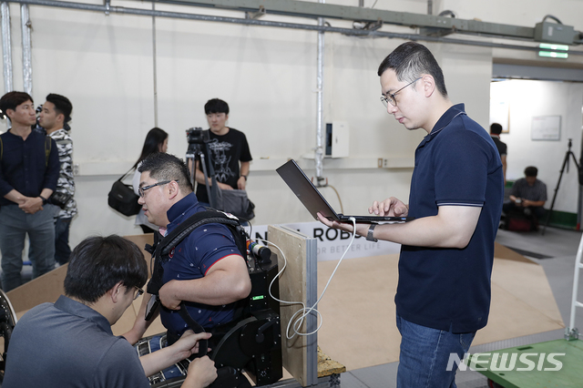 영남대 로봇기계공학과 최정수(오른쪽) 교수가 웨어러블 로봇 워크온슈트를 점검하고 있다.