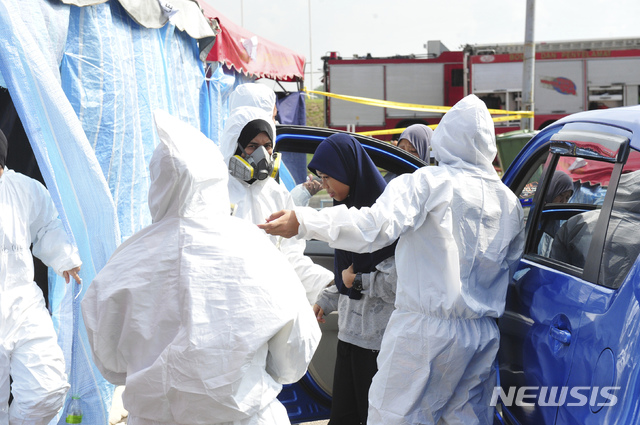 【파시르구당(말레이시아)=AP/뉴시스】말레이시아의 구급 요원들이 25일 남부 조호르주의 파시르구당에서 학생 한 명을 대피시키고 있다. 말레이시아 당국은 이날 환경 오염으로 고통을 호소하는 학생들이 증가함에 따라 111곳의 학교들에 사흘 간 휴교령을 내렸다. 2019.6.25