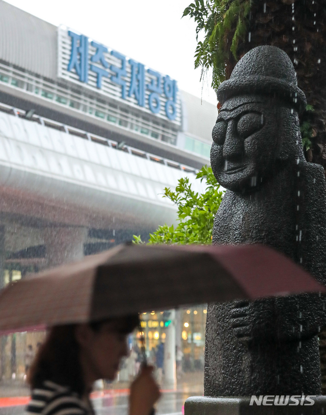 【제주=뉴시스】우장호 기자 = 올해 첫 장맛비가 내린 지난 26일 오전 제주국제공항에 우산을 쓴 관광객이 걸어가고 있다. 2019.06.26. woo1223@newsis.com
