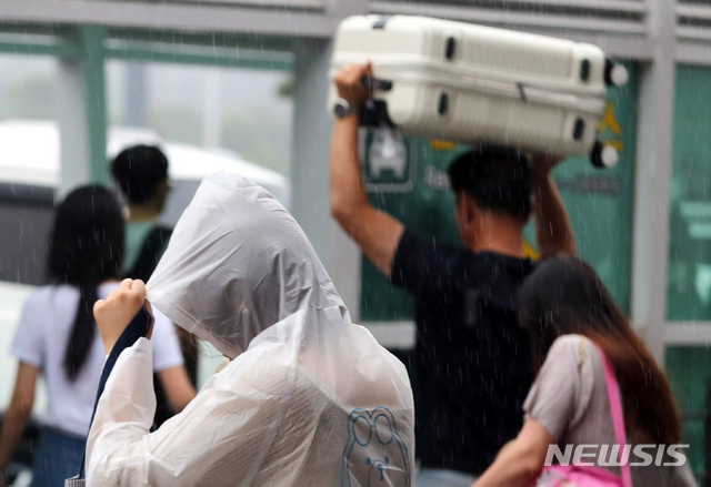 【제주=뉴시스】우장호 기자 = 제주국제공항 이용객들이 비를 피하며 발걸음을 재촉하고 있다. (사진=뉴시스DB) woo1223@newsis.com