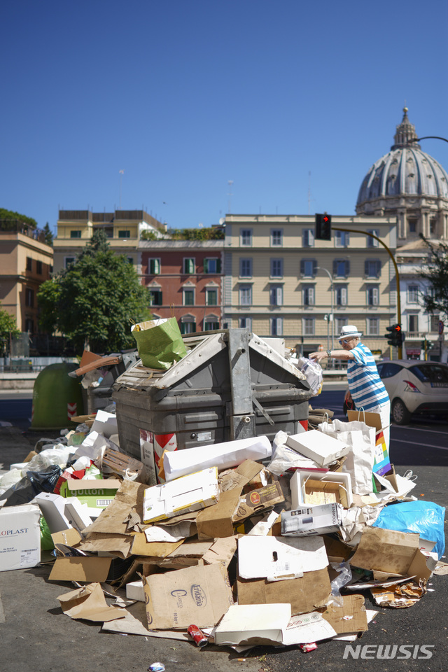 【로마=AP/뉴시스】이탈리아 로마에서 24일(현지시간) 쓰레기가 쌓여있는 가운데 한 남성이 쓰레기를 버리려 하고 있다. 이탈리아 의사단체는 쓰레기가 제때 수거되지 못하고 있는 가운데 폭염에 쓰레기가 부패하면서 시민들의 건강을 해칠 수있다고 경고했다. 2019.06.26