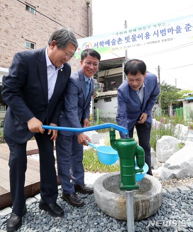 【전주=뉴시스】윤난슬 기자 = 3일 전북 전주시 서학예술촌 빗물정원(서학파출소)에서 '서학예술촌 빗물이용 시범마을 조성 사업' 준공식이 열리고 있다. 사진은 박병술 전주시의회 의장이 서학파출소 내 마련된 소형 빗물정원서 우물 펌프를 작동시켜보는 모습.2019.07.03.(사진=전주시 제공) photo@newsis.com&nbsp; 