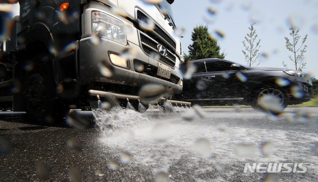 【서울=뉴시스】 고범준 기자 = 서울과 경기에 폭염주의보가 발령된 지난 4일 서울 송파구 올림픽공원 일대 도로에서 송파구청 관계자들이 살수차를 이용해 도로에 물을 뿌리고 있다. 2019.07.04. bjko@newsis.com