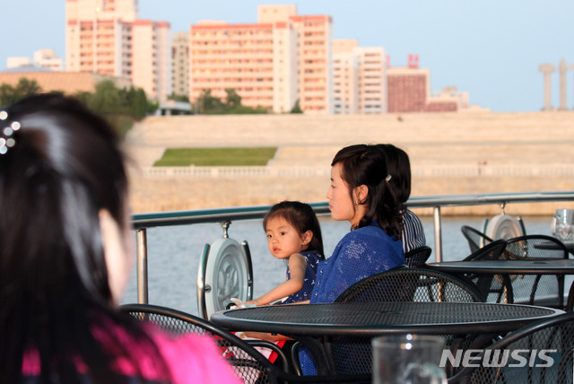 【서울=뉴시스】박진희 기자 = 지난달 방북한 한 해외동포가 평양시 대동강을 운행하는 식당유람선 '대동강호'에서 최근 평양시 풍경을 촬영했다. 머니투데이 미디어그룹 부설 평화경제연구소가 사진들을 단독 입수해 소개한다.&nbsp; 대동강호에서 평양 경치를 감상하는 모녀. 오른쪽 위에 조선로동당 창건 50주년 기념탑이 보인다. 인근에 주체사상탑이 있다. 2019.07.13. (사진=평화경제연구소 제공) photo@newsis.com