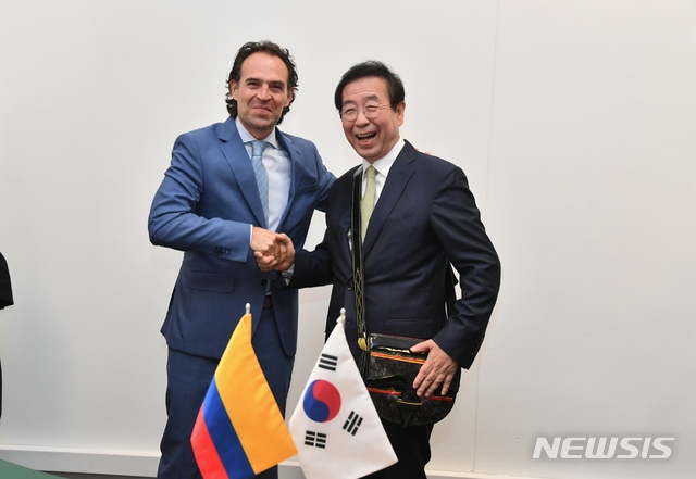 【메데진(콜롬비아)=뉴시스】중남미를 순방중인 박원순(오른쪽) 서을시장은 12일 오전 8시(현지시간) '2019 세계도시정상회의 시장포럼'이 열리고 있는 콜롬비아 메데진 플라자메이어에서 페데리코 구티에레즈 메데진 시장과 면담 중 악수를 나누며 웃고 있다. 이들은 강소 혁신도시 메데진과 우호도시의 물꼬를 트는 '서울시-메데진시 간 우호협력 결연에 대한 양해각서'를 체결했다. 메데진시 농민들의 삶을 표현하는 가방을 선물 받은 박 시장. 2019.07.12. (사진=서울시 제공)