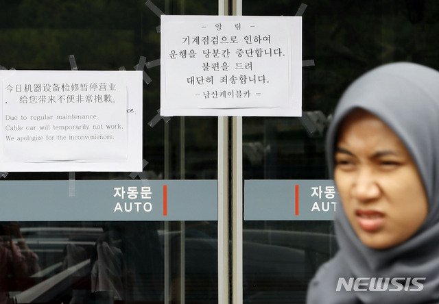 【서울=뉴시스】최동준 기자 = 13일 서울 중구 남산케이블카 매표소에 운행 중단을 알리는 문구 앞으로 외국인 관광객들이 발길을 돌리고 있다.지난 12일 발생한 사고와 관련해 경찰은 당시 케이블카 운행제어 담당자를 입건할 예정이다. 2019.07.13. photocdj@newsis.com