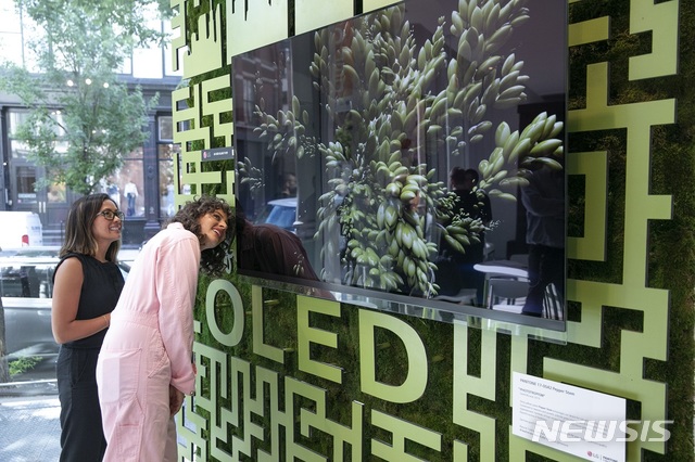 【서울=뉴시스】LG전자가 현지시간 12~14일 미국 뉴욕 맨해튼에서 운영한 '카페 올레드'에서 '아미라 카셈(오른쪽)' 셰프 등이 팬톤이 선정한 올해의 여름 컬러 '페퍼 스템' 조형물 앞&nbsp; LG 올레드 TV를 살펴보고 있다. (사진/LG전자 제공)&nbsp; photo@newsis.com