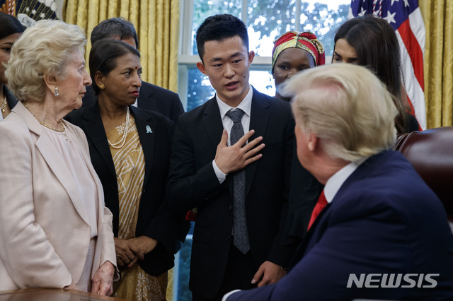 【워싱턴=AP/뉴시스】도널드 트럼프(오른쪽) 미국 대통령이 17일(현지시간) 백악관 집무실에서 종교 박해 피해자들을 만나 탈북민 기독교 신자 주일용 씨의 얘기를 듣고 있다. 트럼프 대통령은 17개국에서 온 종교박해 생존자 27명을 집무실에서 만나 이들의 경험을 들었으며 여기에는 북한과 중국 이외에 뉴질랜드, 예멘, 쿠바, 터키, 이란, 미얀마인 등이 포함됐다. 2019.07.18.