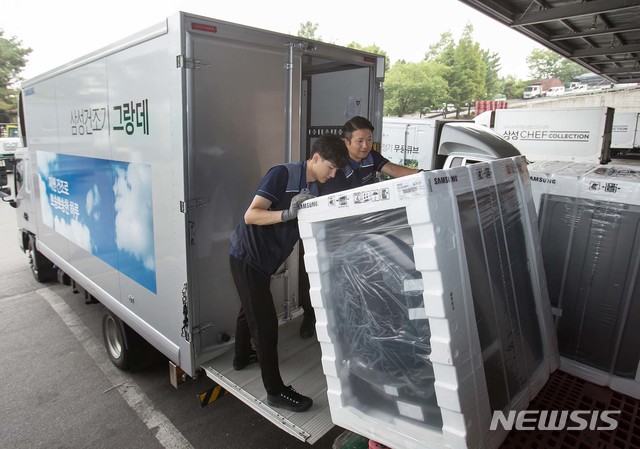 【서울=뉴시스】삼성전자 제품 배송·설치 담당자들이 17일 경기도 고양시 일산서구에 위치한 삼성전자 서서울물류센터에서 삼성 건조기 그랑데를 배송하기 위해 차량에 싣고 있다. 삼성 건조기 그랑데는 높은 습도로 인해 빨래가 잘 마르지 않는 장마철 필수 가전으로 인기를 얻고 있다. 2019.07.18. (사진=삼성전자 제공) photo@newsis.com
