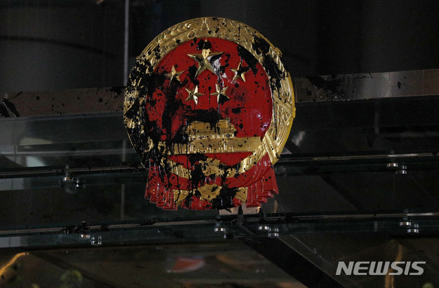 The National Emblem of the People's Republic of China is covered in black paint thrown by protesters outside the Chinese Liaison Office in Hong Kong, Sunday, July 21, 2019. Protesters in Hong Kong pressed on Sunday past the designated end point for a march in which tens of thousands repeated demands for direct elections in the Chinese territory and an independent investigation into police tactics used in previous demonstrations. (AP Photo/Bobby Yip)