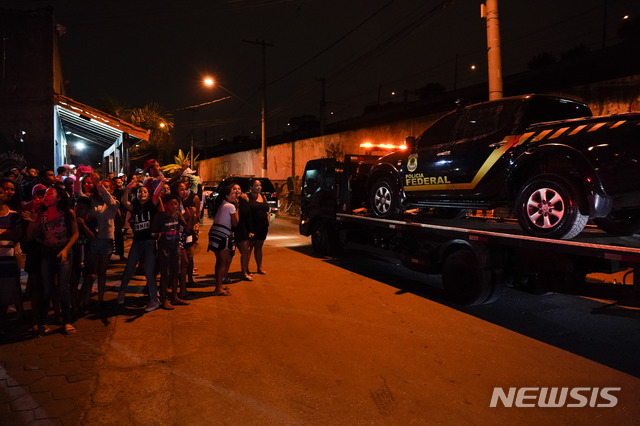 【리우데자네이루=AP/뉴시스】 브라질 상파울루의 구아룰류스 국제공항에서 25일 무려 750km의 금괴를 탈취해 달아난 용의자들이 범행에 사용한 경찰차량으로 위장한 반트럭들을 사람들이 구경하고 있다.  