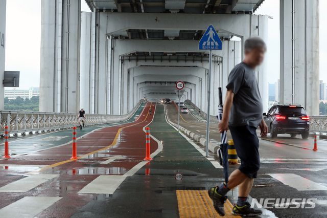 [서울=뉴시스] 이윤청 기자 = 장맛비가 막바지에 다다른 28일 오전 서울 서초구 잠수교에서 한 시민이 우산을 접은 채 횡단보도를 건너고 있다. 기상청에 따르면 장마전선이 이날 오후 중부지방에서 북상하면서 장마는 종료될 예정이다. 2019.07.28. radiohead@newsis.com