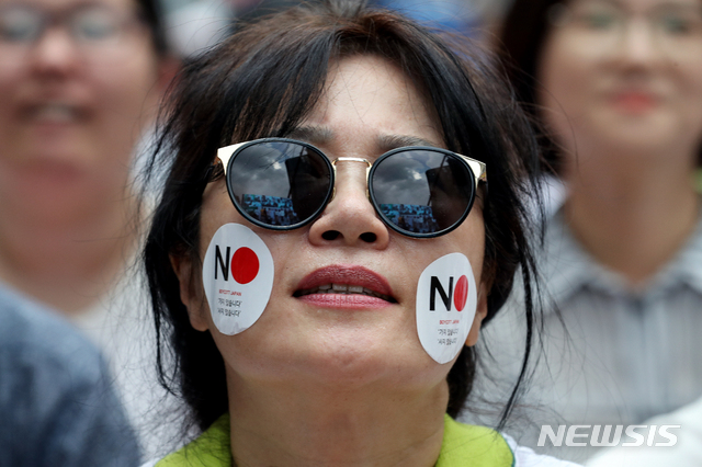 【서울=뉴시스】김병문 기자 = 3일 오후 서울 종로구 일본대사관 앞에서 역사왜곡·경제침략·평화위협 아베규탄 시민행동(아베규탄시민행동) 주최로 열린 ‘아베 규탄 3차 촛불문화제’에 참석한 시민이 얼굴에 반일 스티커를 붙이고 있다. 2019.08.03. dadazon@newsis.com