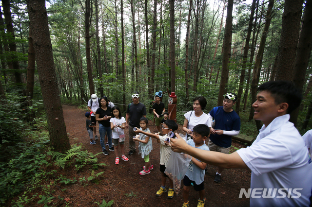【평창=뉴시스】김경목 기자 = 용평리조트를 찾은 가족단위 피서객들이 4일 오후 강원도 평창군 리조트 내 발왕산 국유림 국민의 숲 우정숲길에서 비전혁신팀 프로그램 진행자의 안내를 받으며 다람쥐가 먹을 도토리 숲에 놓아두기, 자연학습, 산림욕, 아로마(사람에게 이로운 식물의 향기) 체험, 밧줄 놀이터에서 숲과 놀기 등 '발왕산과 함께' 프로그램을 즐기며 행복한 휴가를 보내고 있다. 어린이들이 프로그램 진행자 박재화 사원의 설명을 듣고 물총을 쏘듯이 도토리를 숲을 향해 발사하고 있다. 2019.08.04. photo31@newsis.com
