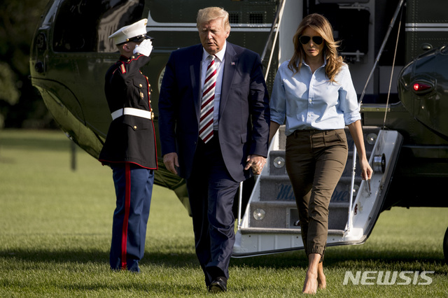 【워싱턴=AP/뉴시스】4일(현지시간) 워싱턴 백악관에 도착해 전용기에서 내린 도널드 트럼프 대통령과 부인 멜라니아 여사가 손을 잡고 걷고 있다. 트럼프 대통령은 하루 사이 최소 29명이 사망한 최악의 총격 사건이 벌어졌는데도 뉴저지주 베드민스터 골프클럽에서 주말을 보냈다는 비판을 받고 있다. 2019.08.05.