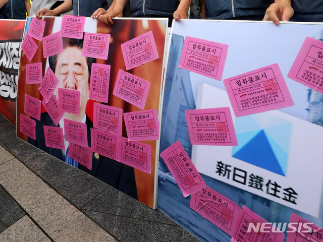 【서울=뉴시스】박주성 기자 = 법원 노조가 7일 오전 서울 종로구 주한 일본대사관 앞에서 대법원 강제징용 판결 부정하는 아베 정권 규탄 법원공무원 기자회견 중 아베 사진과 일본 전범기업 사진에 압류물표시 스티커를 붙이고 있다. 2019.08.07. park7691@newsis.com