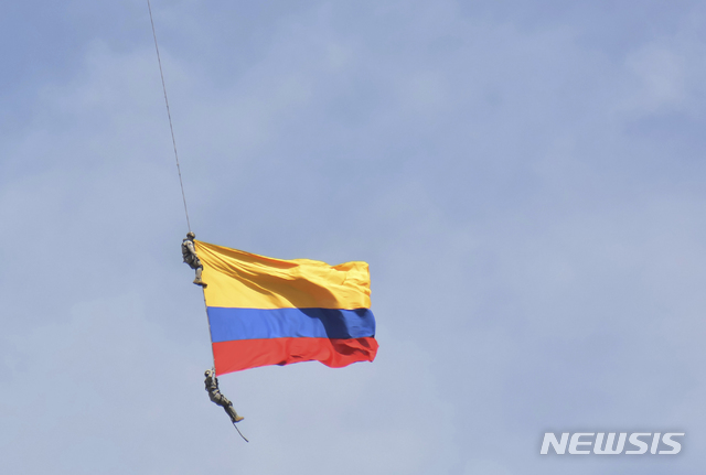 【메델린 (콜롬비아)=AP/뉴시스】 콜롬비아의 메델린에서 11일(현지시간) 열린 60여년 전통의 꽃 축제에서 공군 병사 2명이 헬기의 로프에 매달려 국기를 펼쳐보이는 묘기를 하고 있다. 이들은 잠시 후 로프가 끊기면서 추락해 숨졌다.   