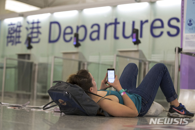 【홍콩=AP/뉴시스】홍콩 시위대의 점거로 항공 운항이 중단된 홍콩 국제공항 출국장에서 12일(현지시간) 한 여행객이 바닥에 누워 스마트폰을 검색하고 있다.  수천 명의 시위대가 공항 입국장에 몰려들어 12일 항공기 운항을 중단했던 홍콩 국제공항은 13일 오전 운항을 재개했다고 밝혔다. 2019.08.13. 