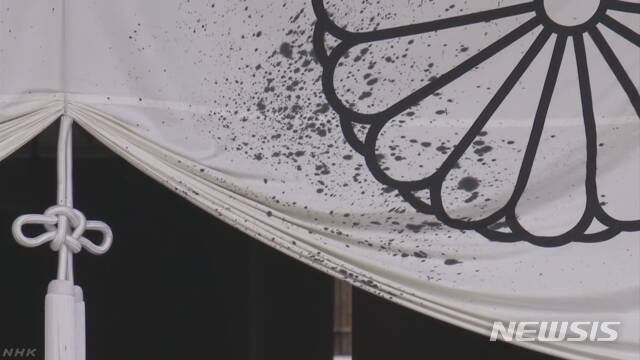 【서울=뉴시스】도쿄의 야스쿠니(靖国) 신사에 먹물로 보이는 액체를 뿌린 남자가 기물 파손 혐의로 체포됐다고 NHK 방송이 19일 보도했다. 일본 왕실의 상진인 국화꽃 문양이 그려진 흰색 천이 뿌려진 액체로 검게 얼룩져 있다. 체포된 남성은 60살 전후로 중국인으로 보인다. <사진 출처 : NHK> 2019.8.18