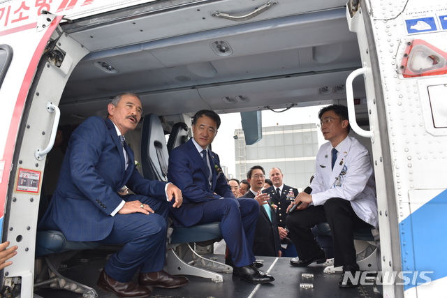 【수원=뉴시스】이국종 경기 남부 권역외상센터장이 6일 낮 경기 수원시 아주대학교병원 옥상 헬리패드에 착륙한 응급의료 전용헬기(닥터헬기)에서 박능후 보건복지부 장관(가운데)과 해리 해리스(왼쪽) 주한미국대사에게 운영 계획 등을 설명하고 있다. 2019.09.06. (사진=보건복지부 제공) photo@newsis.com