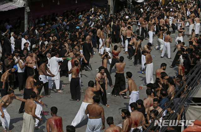 10일 파키스탄 라발핀디에서 무슬림 시아파 신도들이 이맘 후세인의 추모절인 아슈라를 맞아 행진 중 의식인 사슬 채찍으로 자기 몸을 때리며 피를 흘리는 자학 행위를 하고 있다&nbsp;&nbsp; AP
