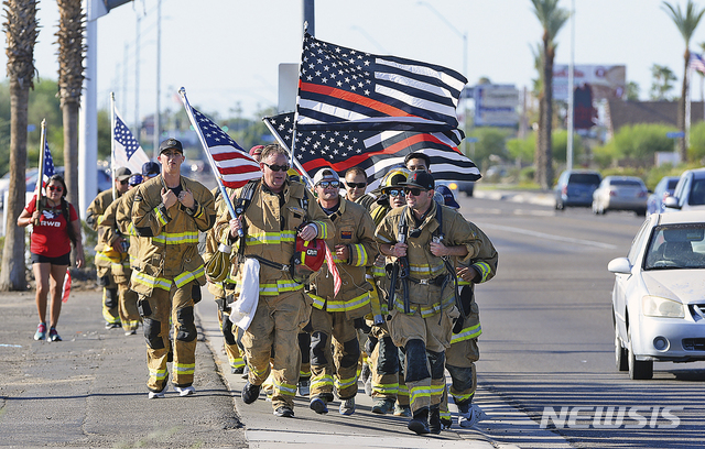 [유마=AP/뉴시스]11일(현지시간) 미 애리조나주 유마의 유마소방국 소속 소방대원들이 미국 국기와 장비 일체를 갖추고 민간인, 유마 공군기지 해병대 구조대, 소방서 직원 등과 함께 연례 '터널 투 타워스' 달리기 행사에 참여해 달리고 있다. 이 행사는 2001년 9월 11일 뉴욕의 세계무역센터 테러 발생 시 인명 구조 작업 중 사망한 뉴욕시 소방관 스테픈 실러의 희생정신을 기리기 위해 만들어졌다. 2019.09.12.