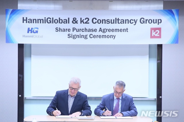 미국 오탁의 제임스 하만 대표(사진 왼쪽)가 한미글로벌 김종훈 회장을 대신해 k2그룹의 존 세트라 대표와 함께 인수계약서에 서명하고 있다.(사진제공=한미글로벌)