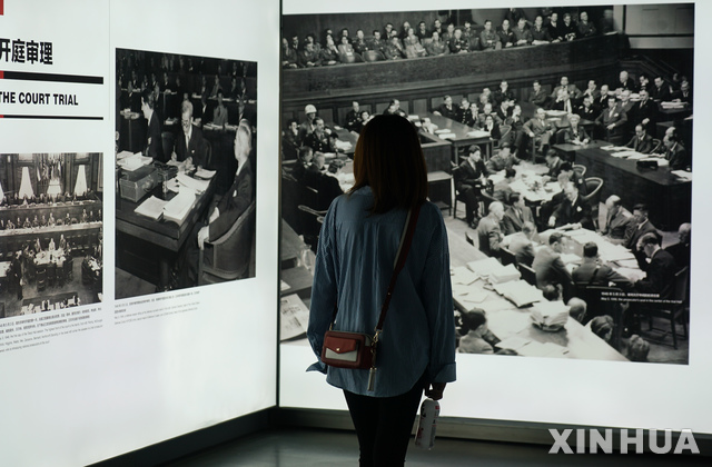 【난징(중국)= AP/뉴시스】 지난 9월 18일 난징에서 열린 난징대학살 71주기 기록사진 전시회에서 한 관람객이 전쟁후의 도쿄 일본군 전범 재판에 관한 사진을 들여다 보고 있다.  이 전시회는 2020년 3월까지 계속된다.   