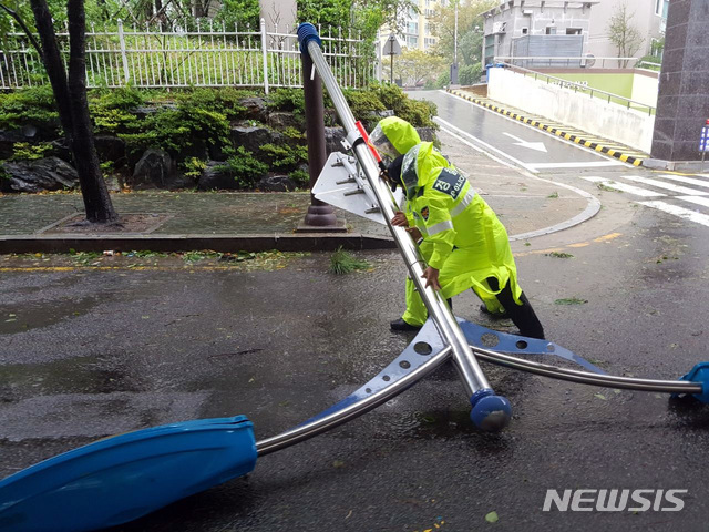 【부산=뉴시스】 제17호 태풍 '타파'(TAPAH)가 북상 중인 22일 부산지역에 태풍경보가 발령된 가운데 수영구 민락교 인근 인도의 가로등이 강풍에 도로로 쓰러진 것을 순찰 중이던 경찰이 발견해 안전조치를 했다. 2019.09.22. (사진=부산경찰청 제공)photo@newsis.com