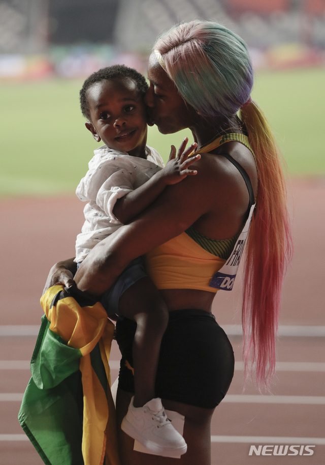 【도하=AP/뉴시스】 셸리 앤 프레이저-프라이스(자메이카)가 지난 2019년9월30일(한국시간) 카타르 도하 칼리파 스타디움에서 열린 2019 도하 세계육상선수권대회 여자 100m 결선에서 10초71의 기록으로 우승한 뒤 아들 지온을 안고 키스하고 있다.