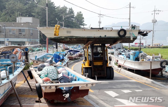 【부산=뉴시스】 하경민 기자 = 제18호 태풍 '미탁'(MITAG)이 북상 중인 지난 30일 부산 해운대구 송정해수욕장 인근 송정어촌계 소속 어민들이 중장비를 동원해 소형 어선을 도로변으로 옮기고 있다. 2019.09.30. yulnetphoto@newsis.com