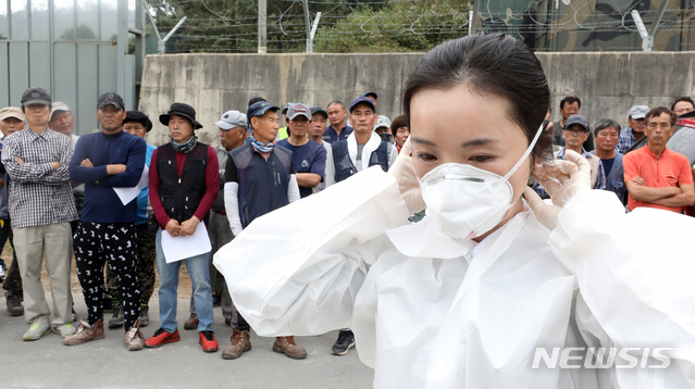 【파주=뉴시스】김병문 기자 = 국내 10번째 아프리카돼지열병(ASF)이 발병한 2일 오전 경기 파주 파평면의 ASF 확진 판정을 받은 돼지 사육 농가 인근에서 파주 보건소 직원이 살처분 작업 관계자들에게 방호복 착용 교육을 하고 있다. 2019.10.02.  dadazon@newsis.com