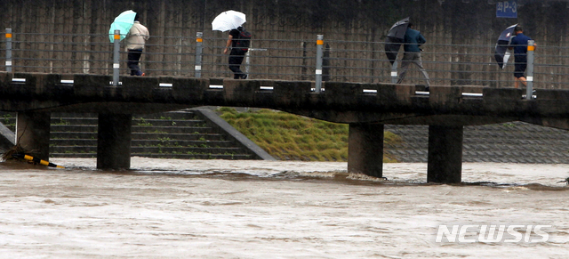 【강릉=뉴시스】김경목 기자 = 제18호 태풍 '미탁(MITAG)'이 몰고 온 폭우가 쏟아진 3일 오후 시민들이 강원 강릉시 남대천 잠수교를 힘겹게 걸어가고 있다. 2019.10.03. photo31@newsis.com
