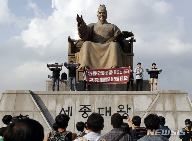 【서울=뉴시스】최동준 기자 = 한국대학생진보연합이 4일 서울 광화문광장 세종대왕 동상에 올라 지소미아 파기 방해, 방위비 분담금 인상 압박 등을 주장하며 미국 규탄 기습시위를 하고 있다. 2019.10.04. photocdj@newsis.com